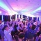 Guests dancing with hands raised on the dance floor under colorful lighting